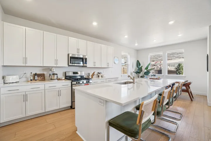 Kitchen featuring a breakfast bar area, stainless steel appliances, light wood finished floors, a kitchen island with sink, and recessed lighting