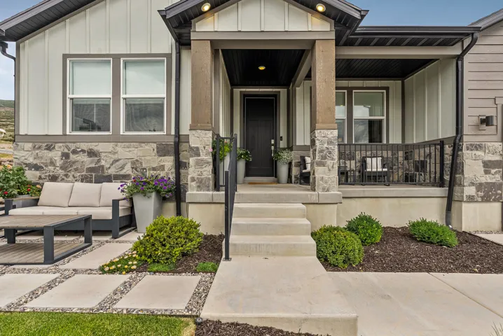 View of exterior entry featuring board and batten siding, a porch, stone siding, and outdoor lounge area