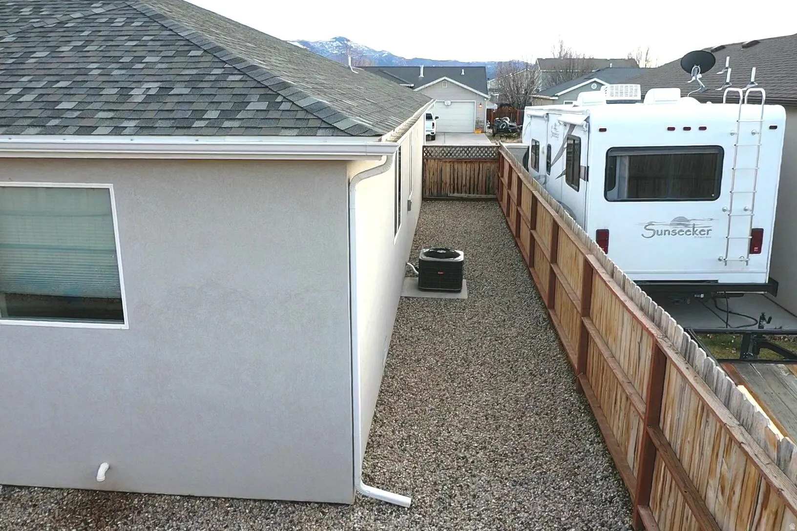 View of side of home featuring a fenced backyard, stucco siding, and a shingled roof