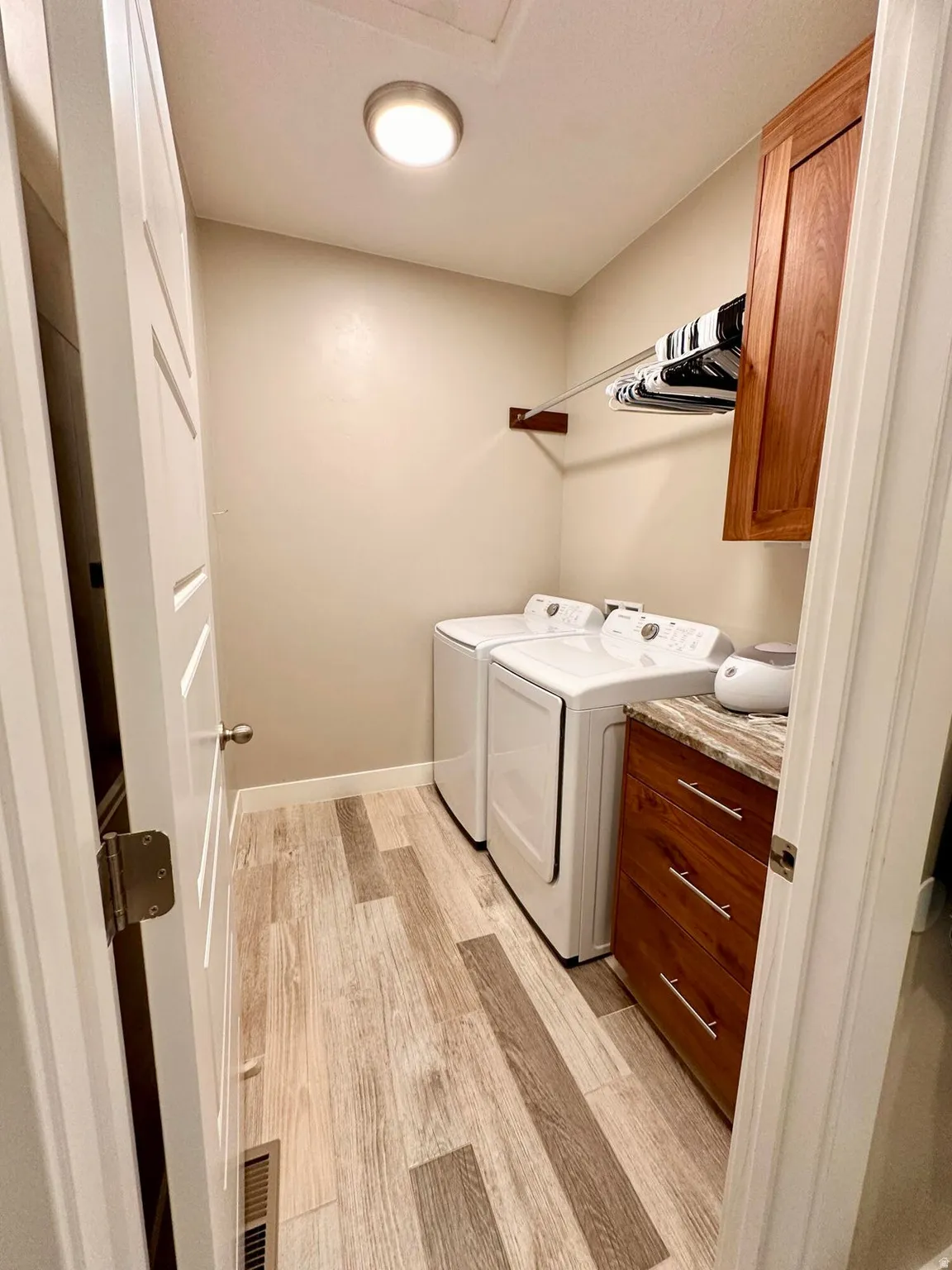 Laundry room with light wood finished floors, cabinet space, and separate washer and dryer