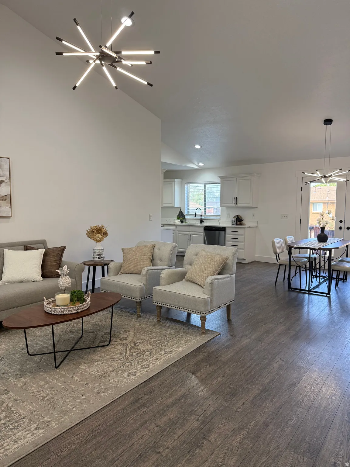 Living area featuring a chandelier, dark wood-type flooring, high vaulted ceiling, and recessed lighting