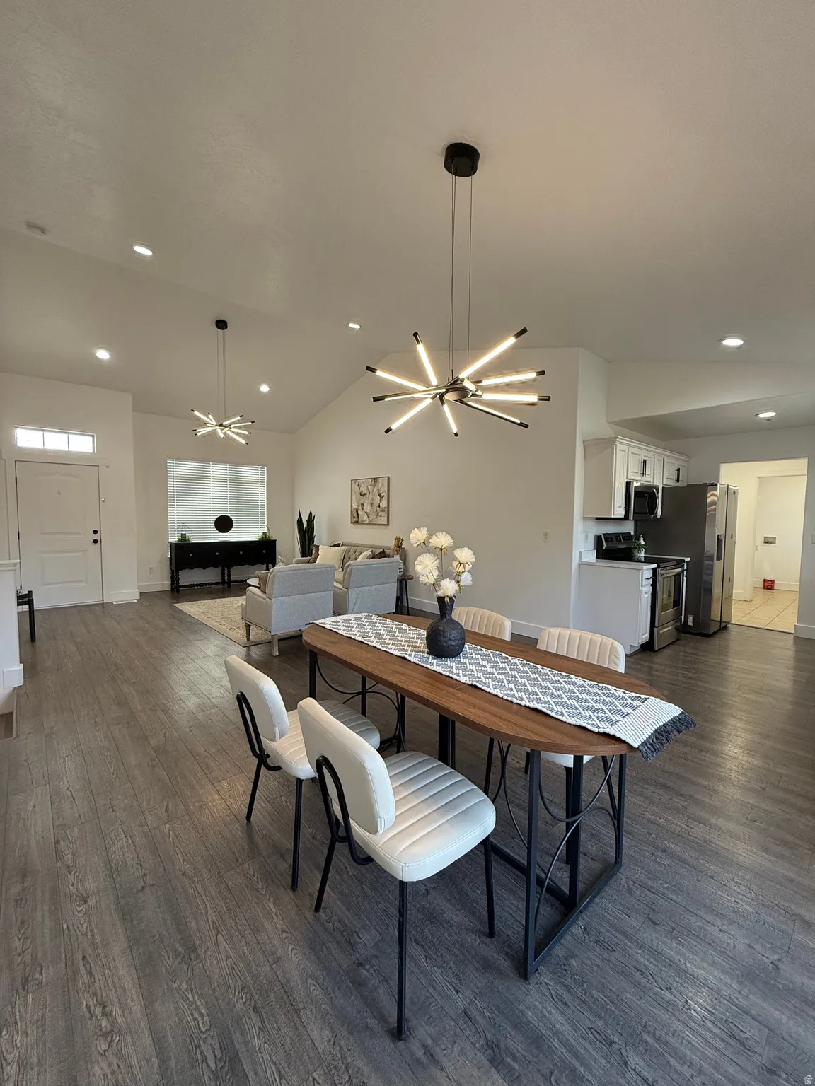Dining area featuring lofted ceiling, recessed lighting, dark wood finished floors, and a chandelier