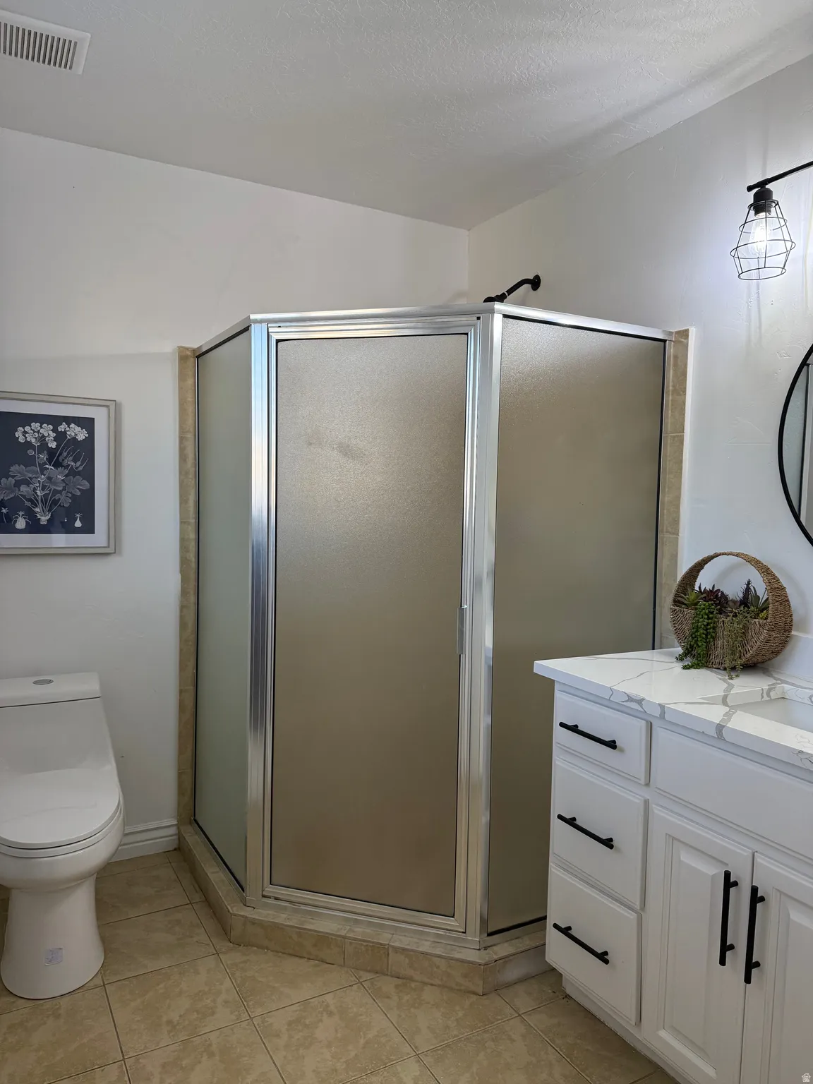 Bathroom featuring a stall shower, vanity, light tile patterned flooring, and a textured ceiling