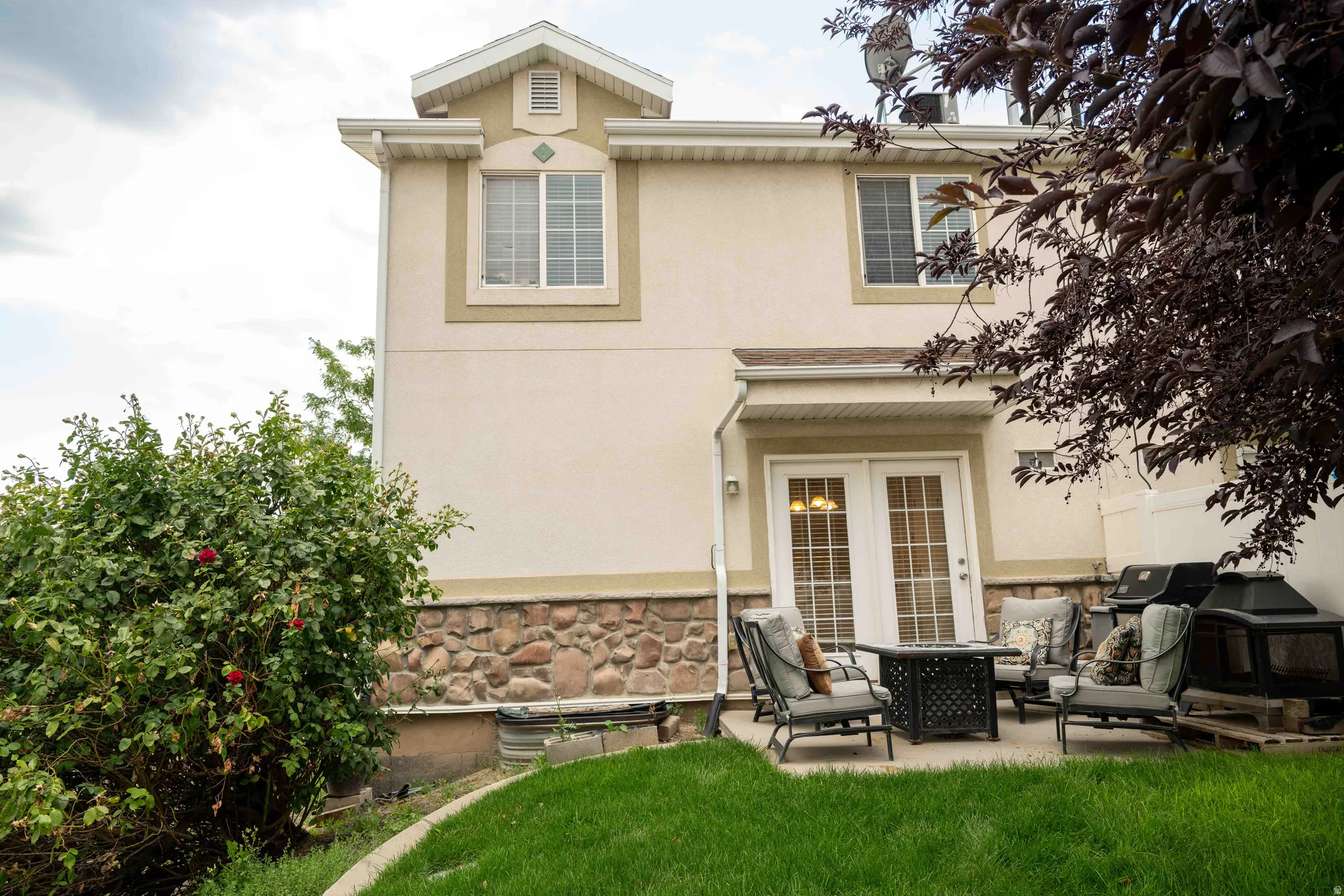 Rear view of property with stucco siding, stone siding, and a patio area