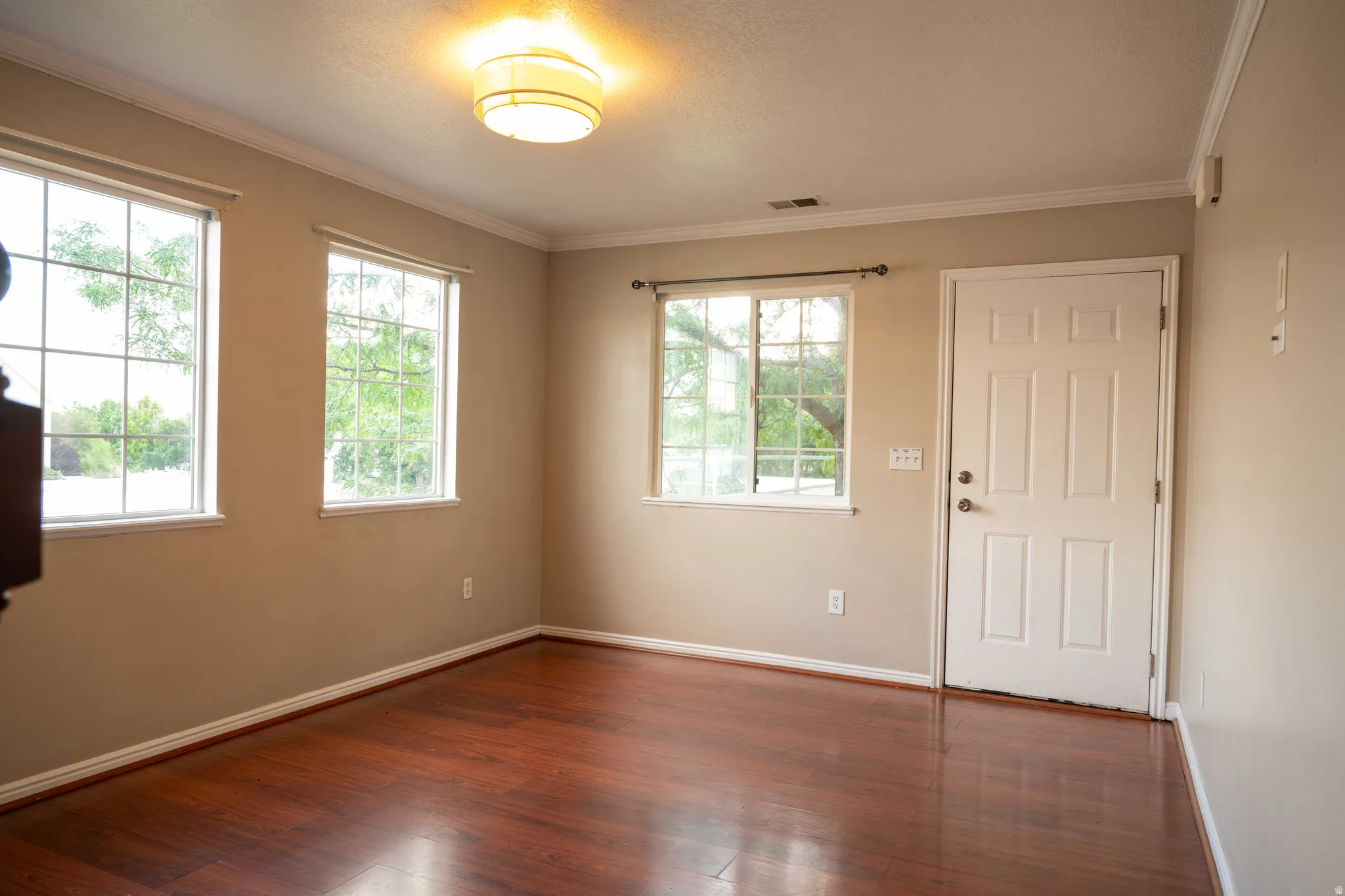 Empty room featuring dark wood-style flooring and ornamental molding