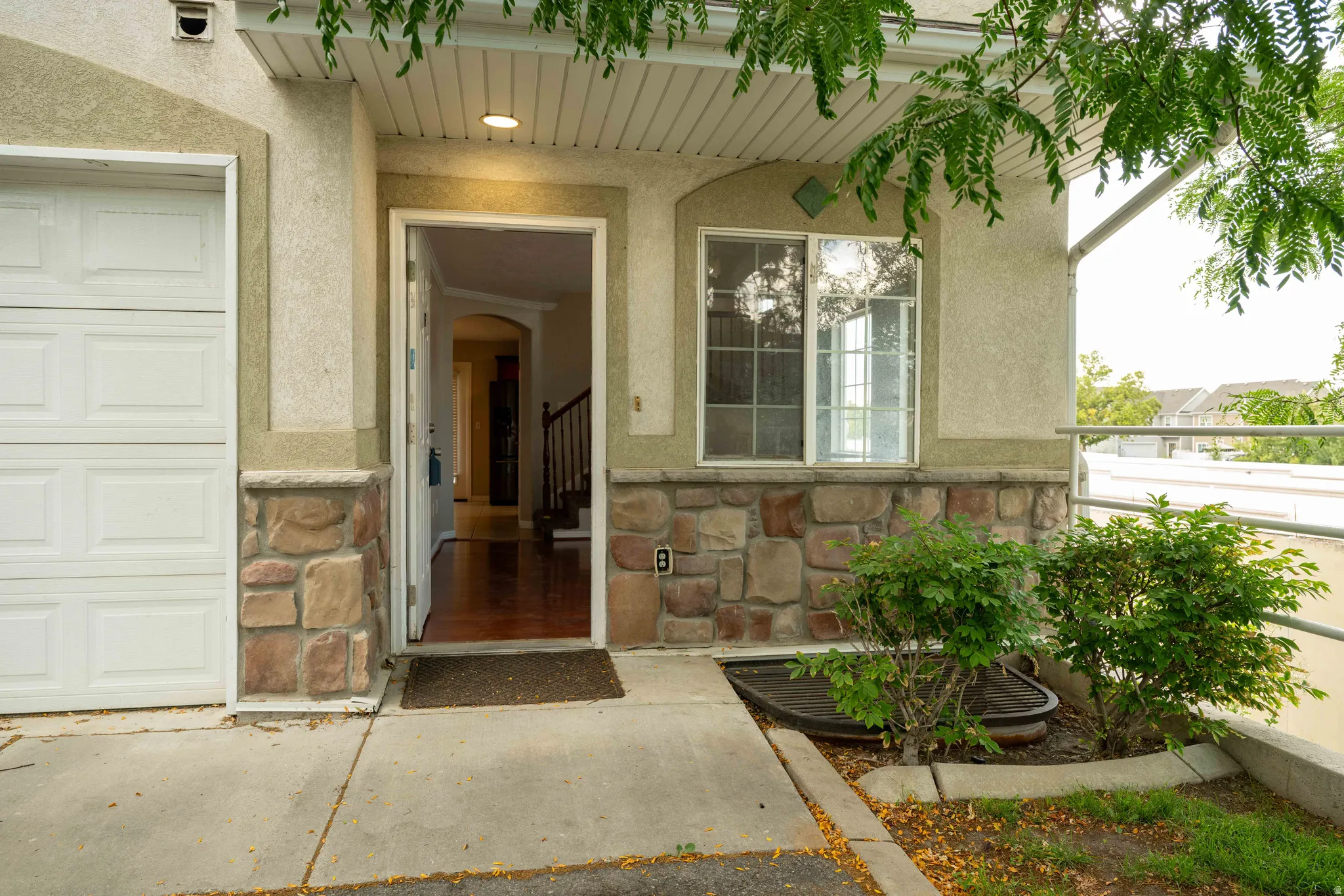 Doorway to property with stone siding, stucco siding, and a garage