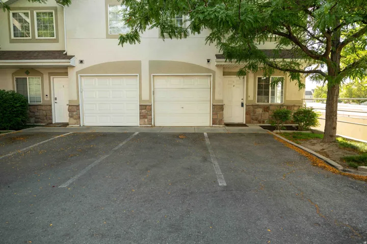 View of front of home featuring stone siding, asphalt driveway, stucco siding, and a garage