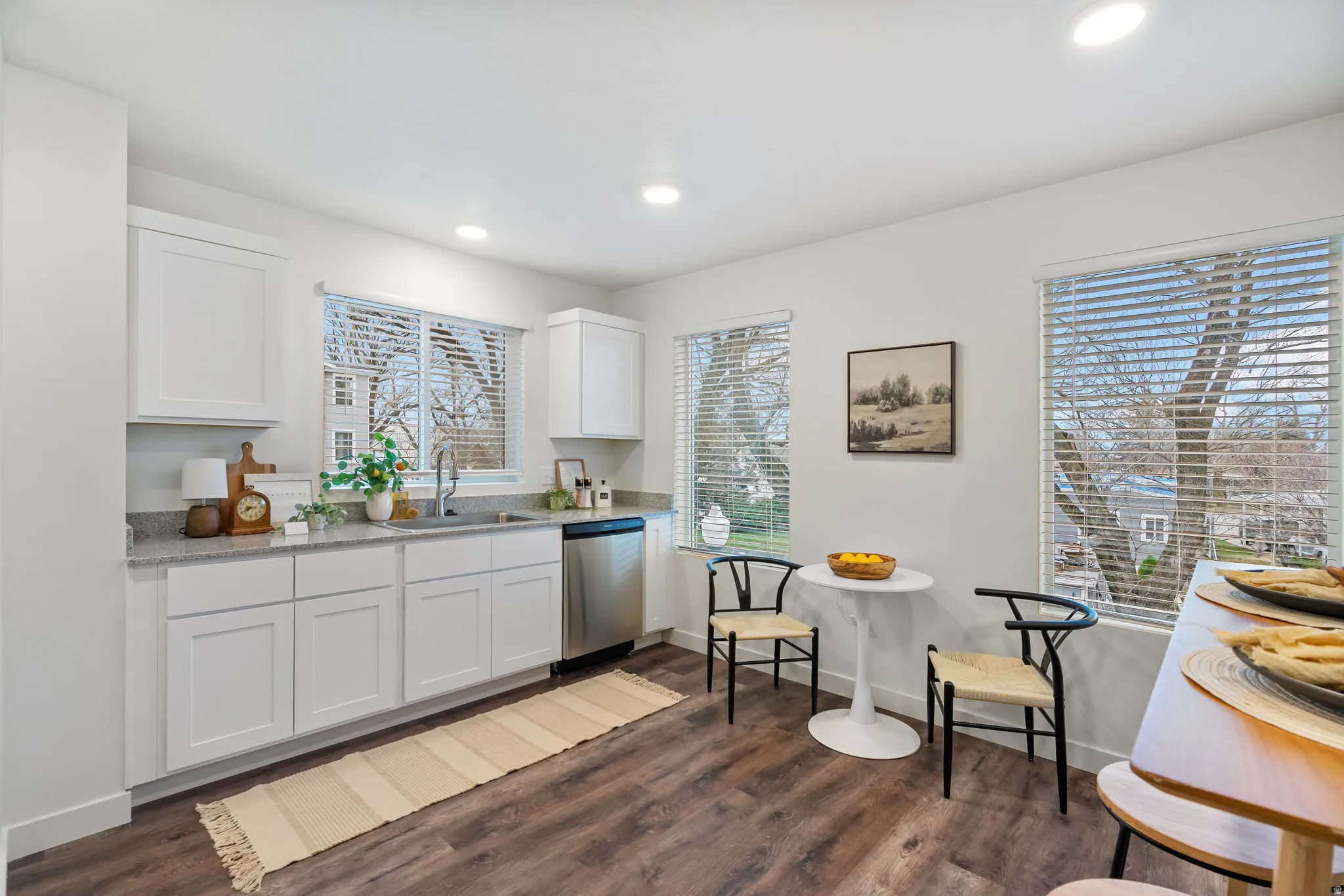 Kitchen featuring white cabinetry, light stone countertops, stainless steel dishwasher, dark wood-type flooring, and recessed lighting