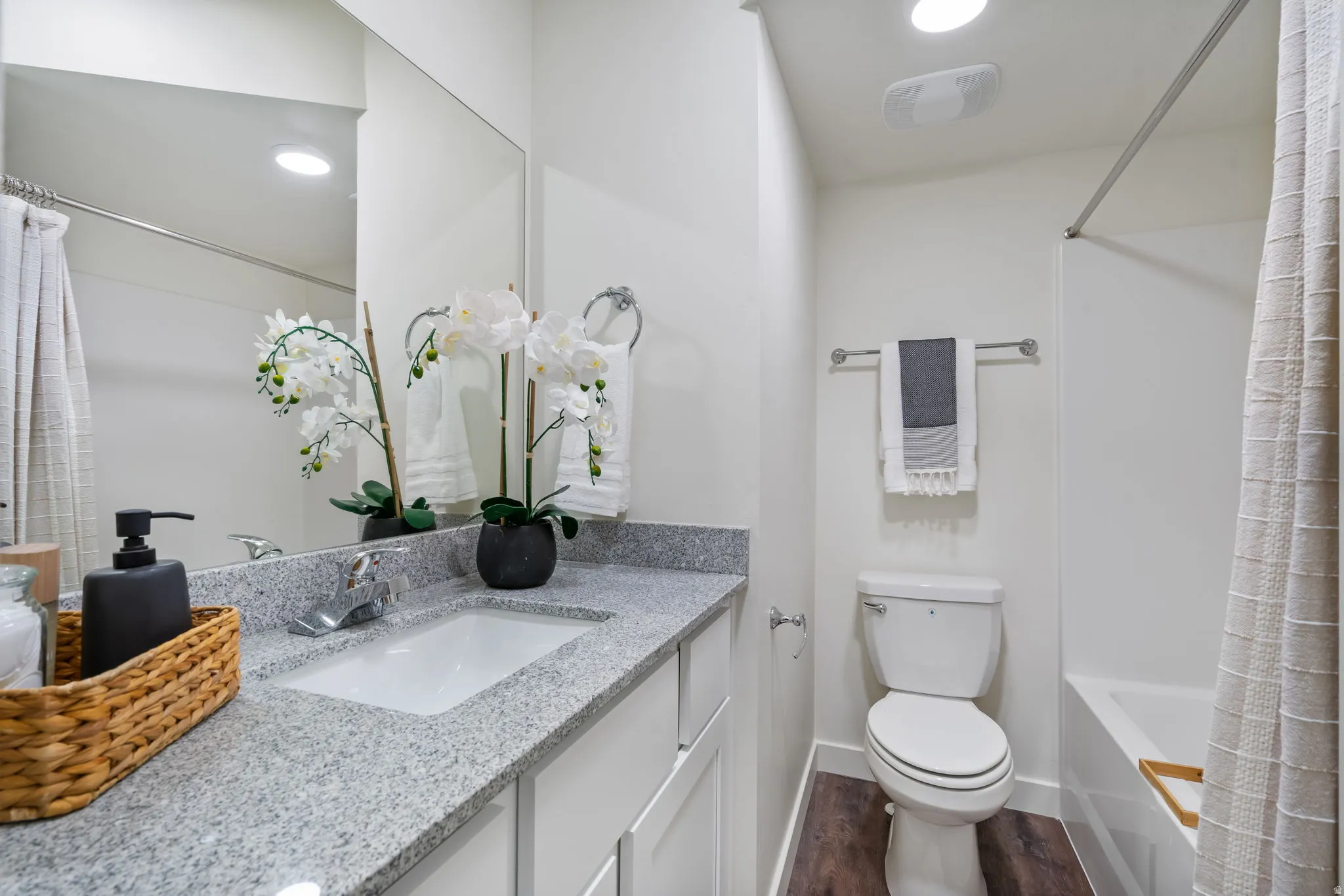 Primary ensuite bathroom featuring vanity, shower / tub combo with curtain, dark wood finished floors, and recessed lighting
