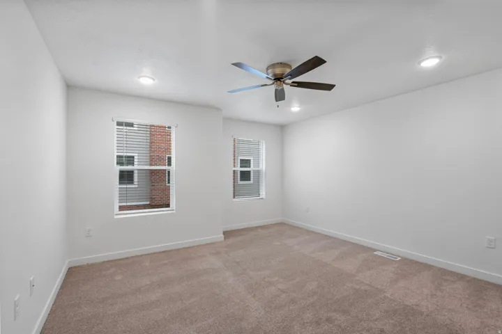Primary bedroom with light carpet, healthy amount of natural light, and ceiling fan