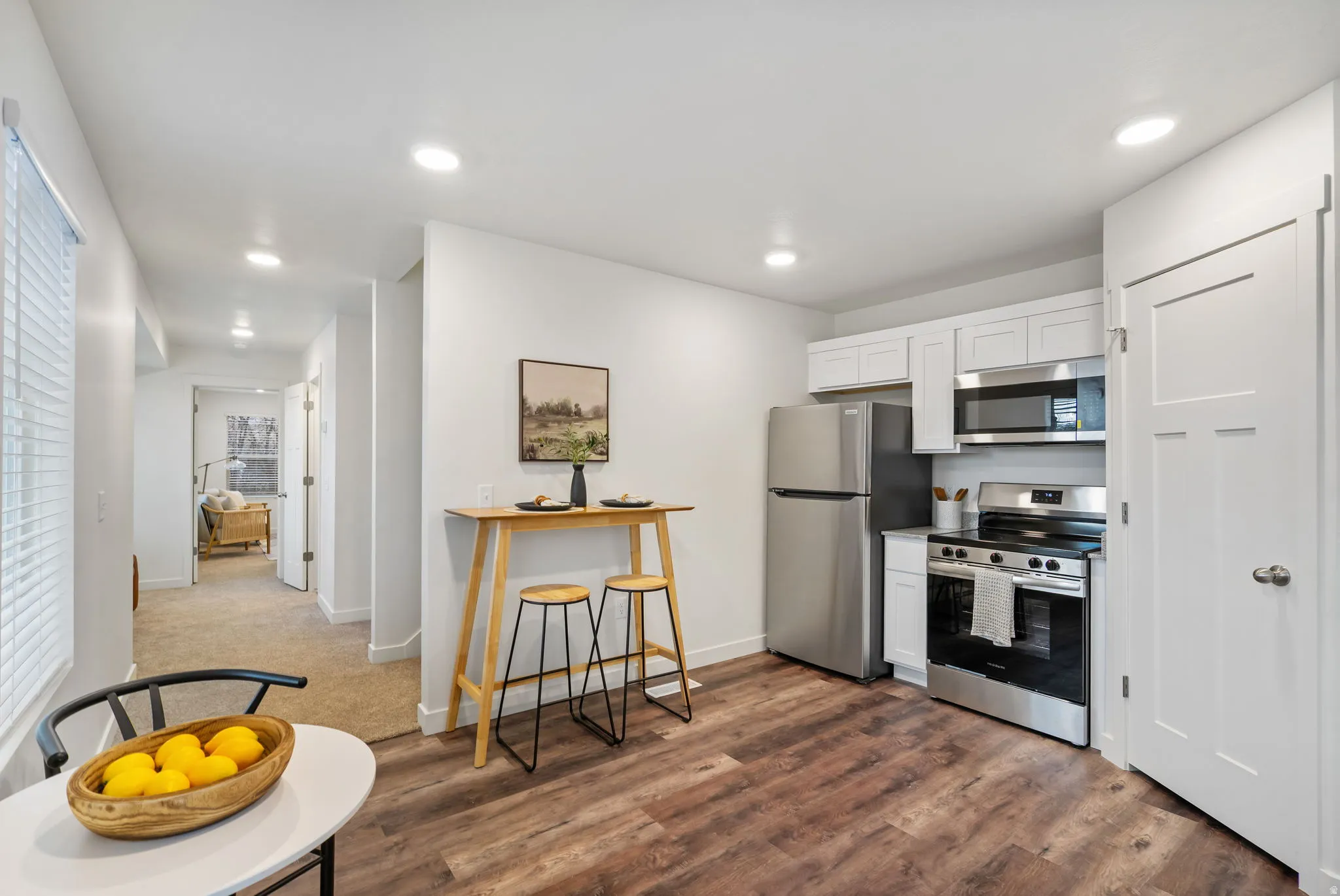 Kitchen featuring white cabinets, appliances with stainless steel finishes, light countertops, dark wood finished floors, and recessed lighting