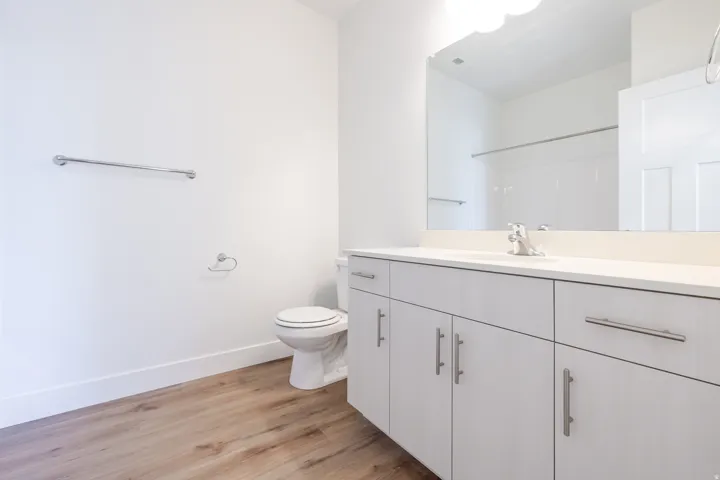 Bathroom featuring a light wood-finish floor, white walls, and a white vanity with silver hardware