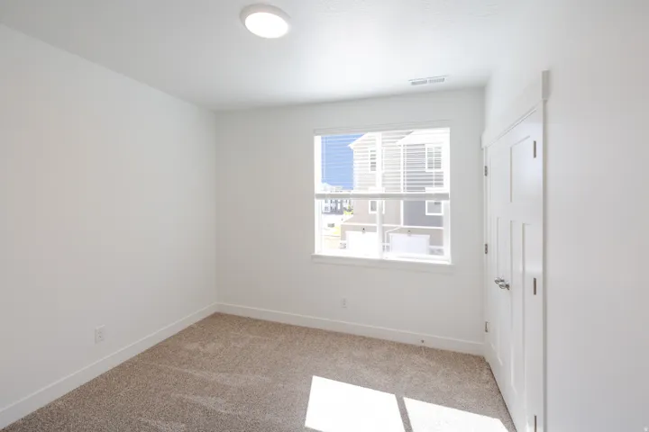 Bright interior space featuring neutral carpeting, white walls, and a modern ceiling light fixture