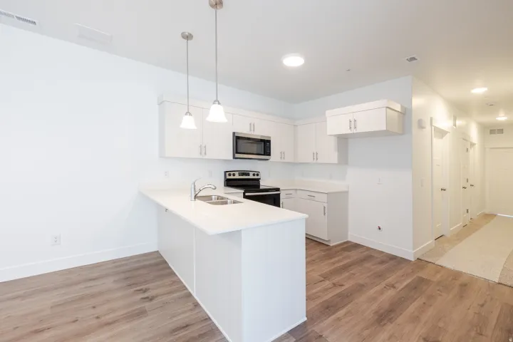 Contemporary kitchen featuring white cabinetry, light-toned countertops, and wood-finish flooring