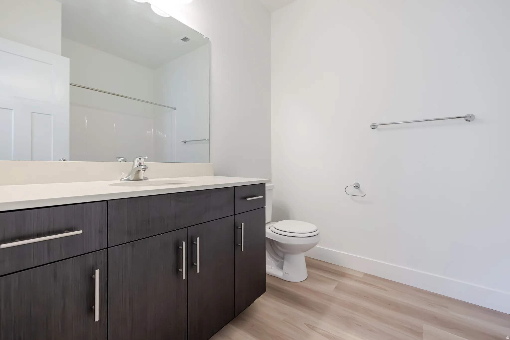 Bathroom featuring a single vanity with a light-toned countertop, dark wood-finish cabinetry, and a chrome faucet