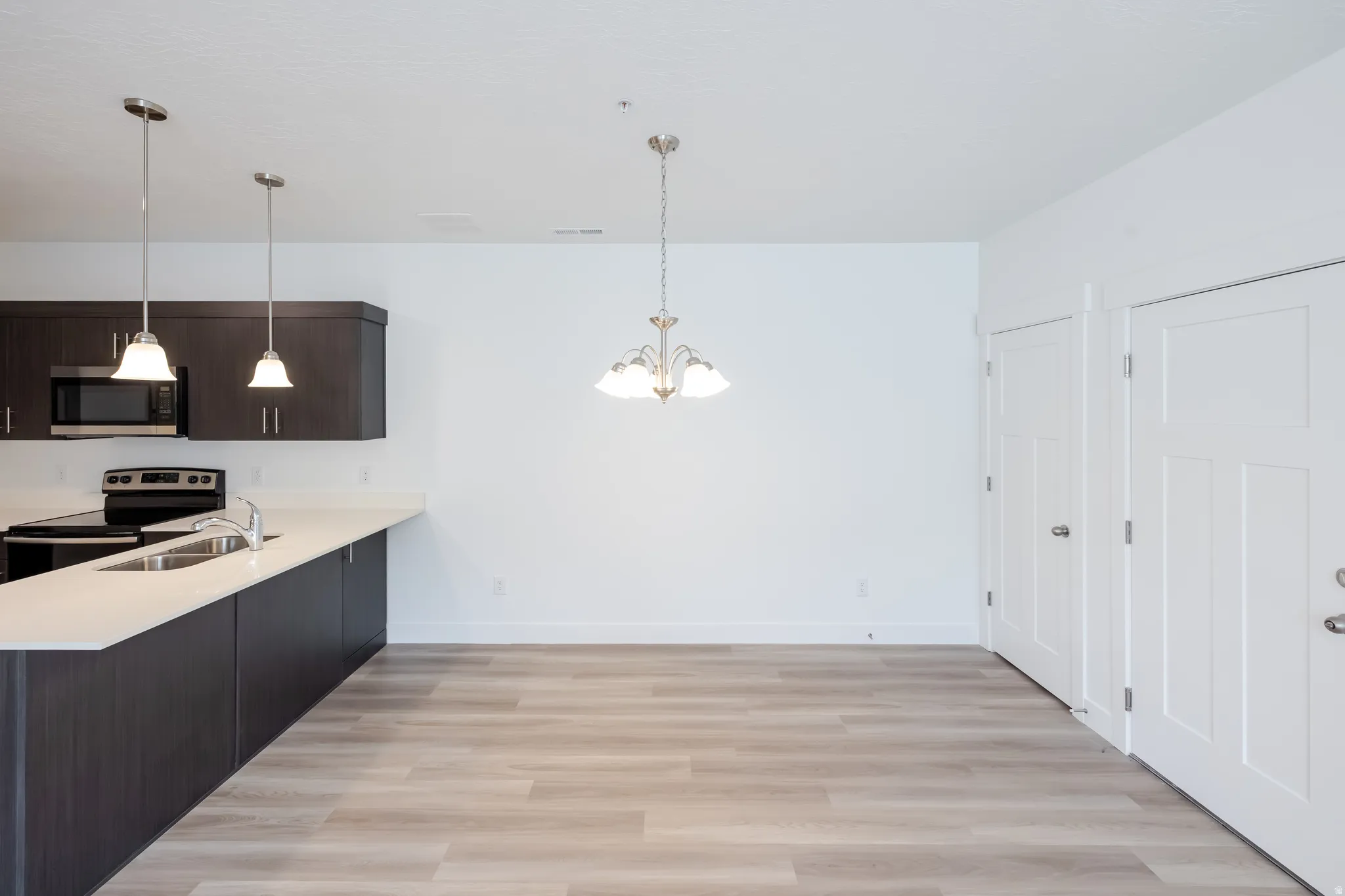 Kitchen with dark wood-finish cabinetry, light countertops, and stainless steel appliances