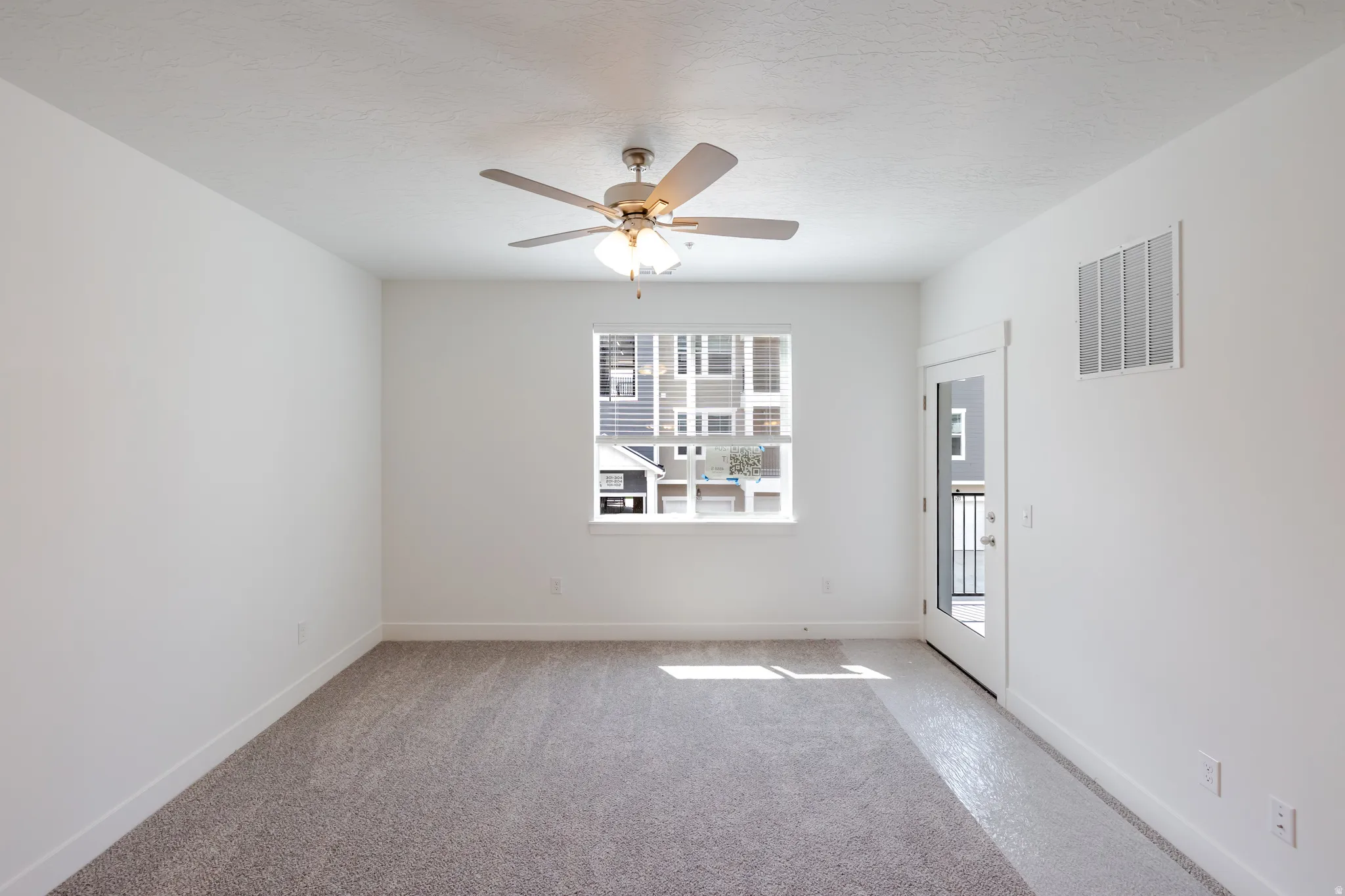 Spacious room featuring neutral carpet flooring, a ceiling fan with integrated lighting, and white walls