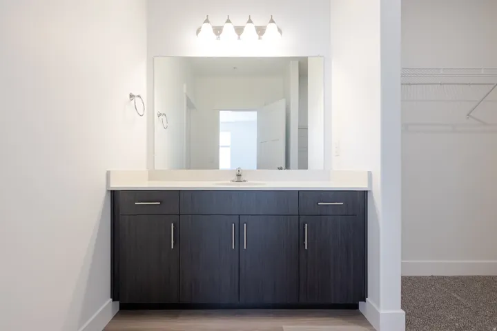 Modern vanity with dark wood-finish cabinetry, chrome hardware, and a white countertop