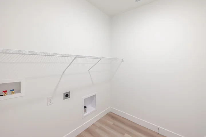 Laundry area with light wood-finish flooring and white baseboards
