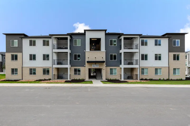 Multi-story building featuring a facade with mixed materials including light-colored brick, white stucco, and gray siding