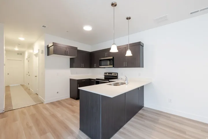 Kitchen featuring dark wood-finish cabinetry, light countertops, and stainless steel appliances