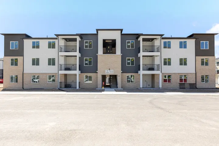 Contemporary multi-story building featuring a facade of light-colored brick, white siding, and dark gray siding