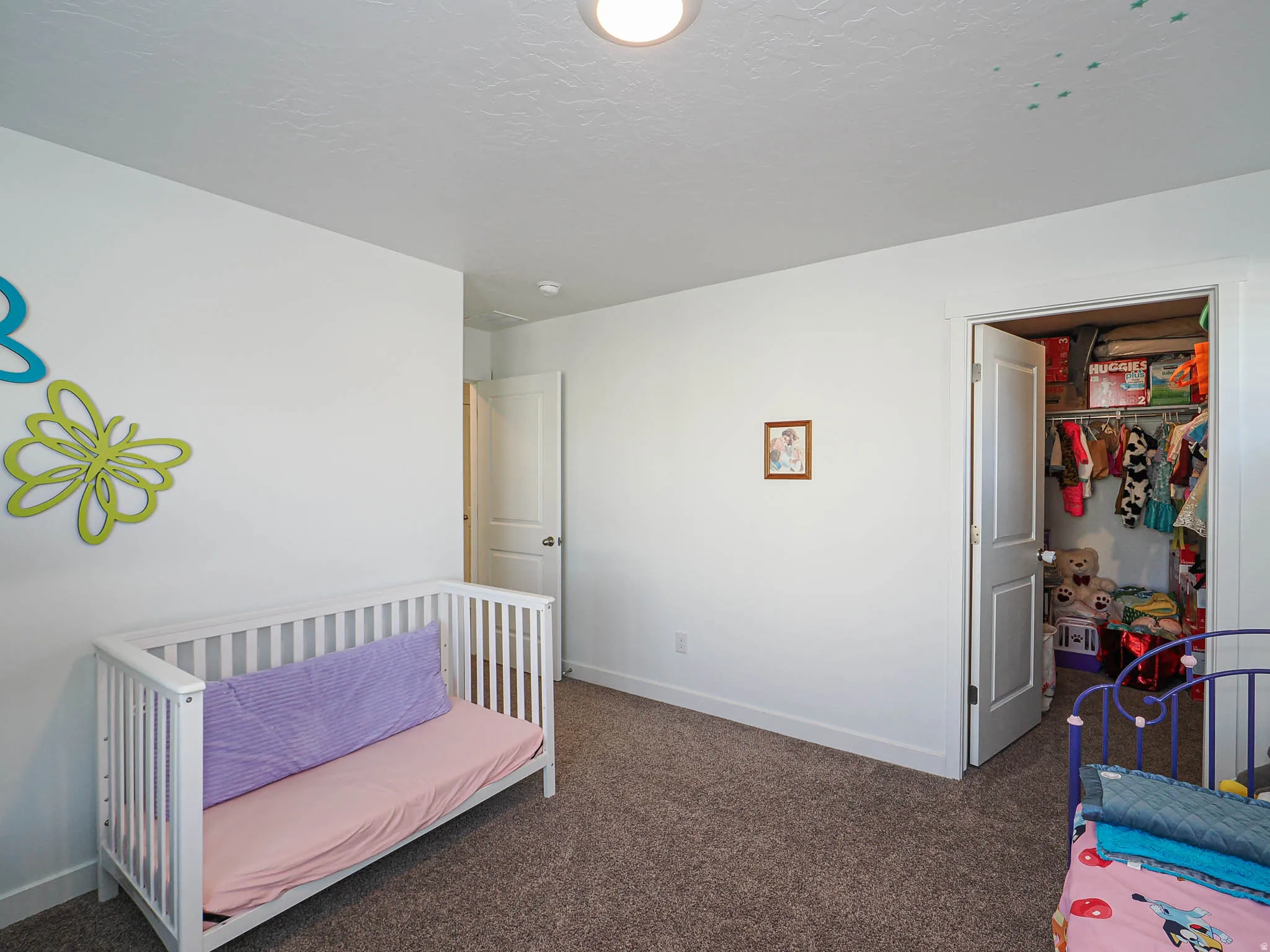 Bedroom with a spacious closet, dark colored carpet, and a textured ceiling
