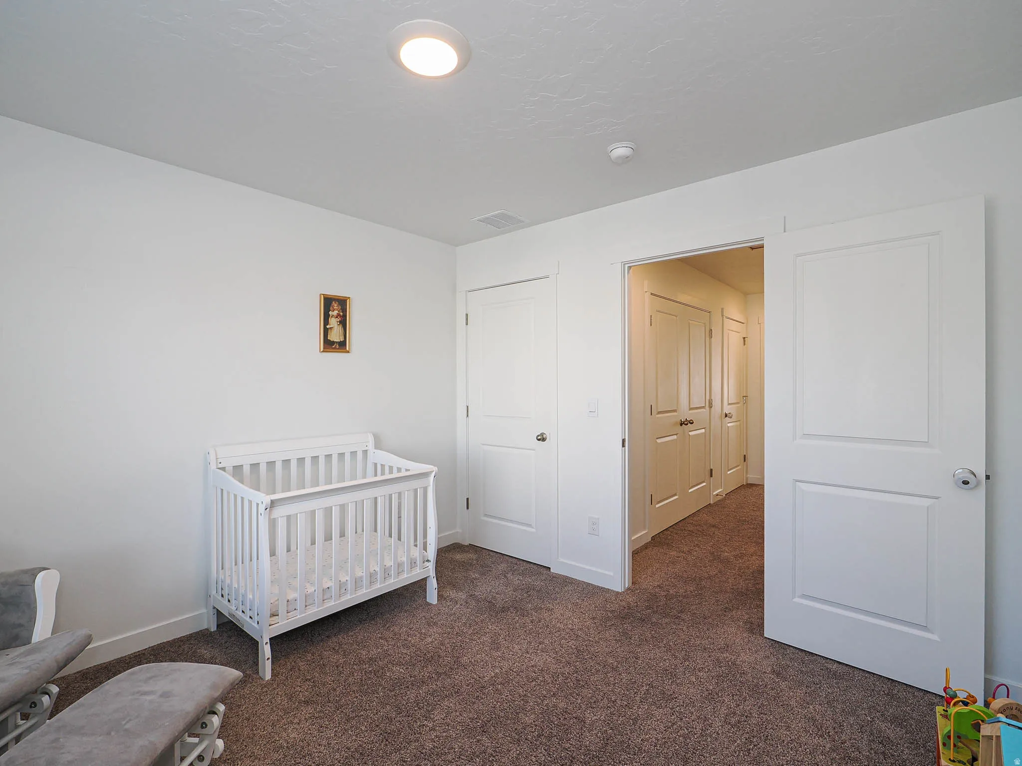 Bedroom featuring a crib and dark carpet