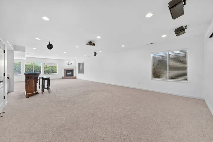 Spacious room featuring neutral carpet flooring, recessed lighting, and a brick fireplace