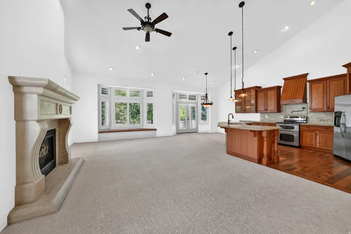 Vaulted ceilings throughout this open-concept room, featuring a stone fireplace and bay windows
