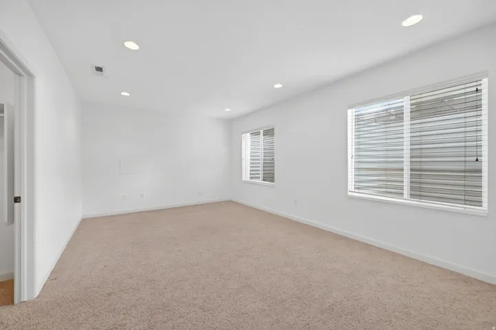 Spacious room featuring neutral carpet flooring, recessed lighting, and white walls