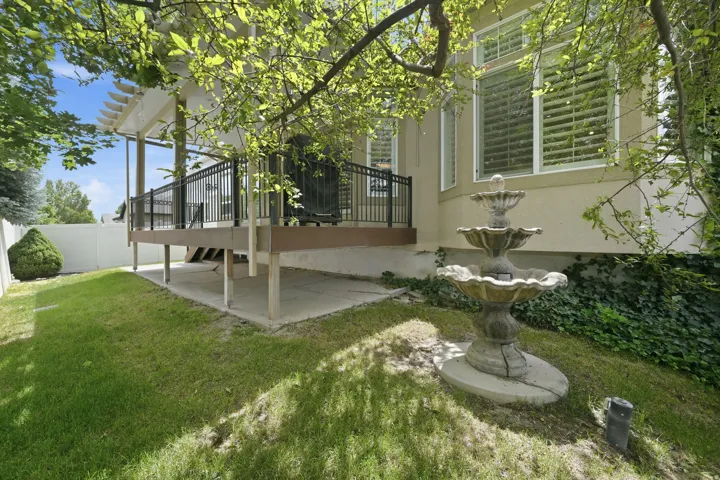 Expansive backyard featuring a multi-tiered water fountain, manicured lawn, and mature trees