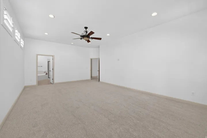 Spacious room featuring vaulted ceilings with recessed lighting, an overhead ceiling fan, and light-toned carpeting