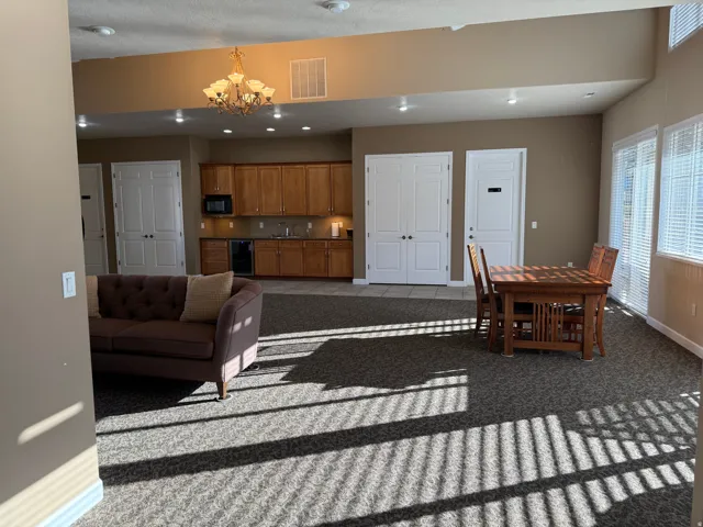 Clubhouse carpeted living area featuring baseboards and a chandelier