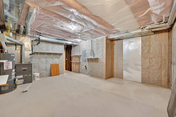 Unfinished basement with strapped water heater and electric panel