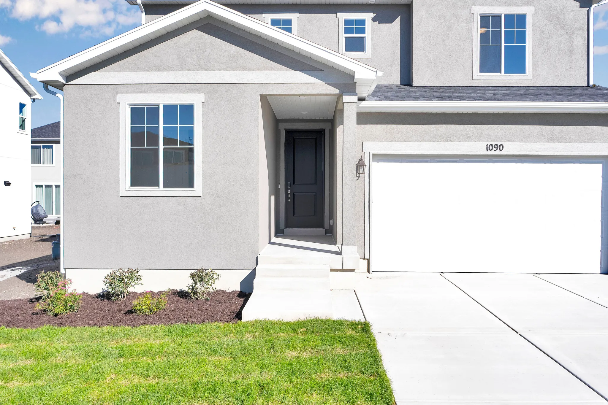 Doorway to property featuring stucco siding, an attached garage, concrete driveway, and a lawn