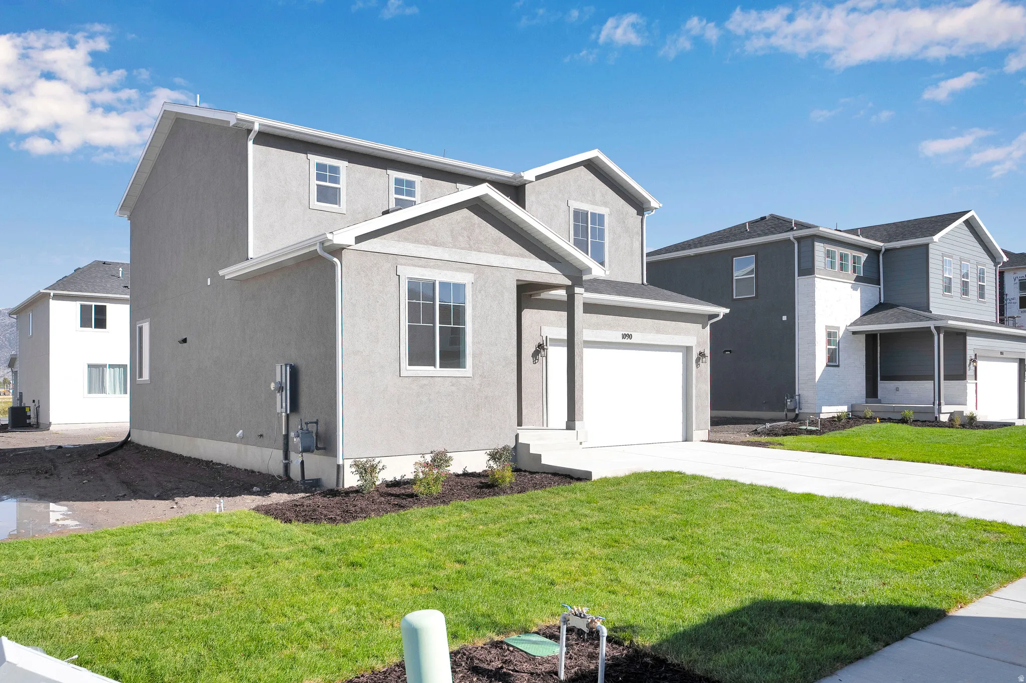 Traditional-style house featuring stucco siding, a garage, driveway, and a front yard