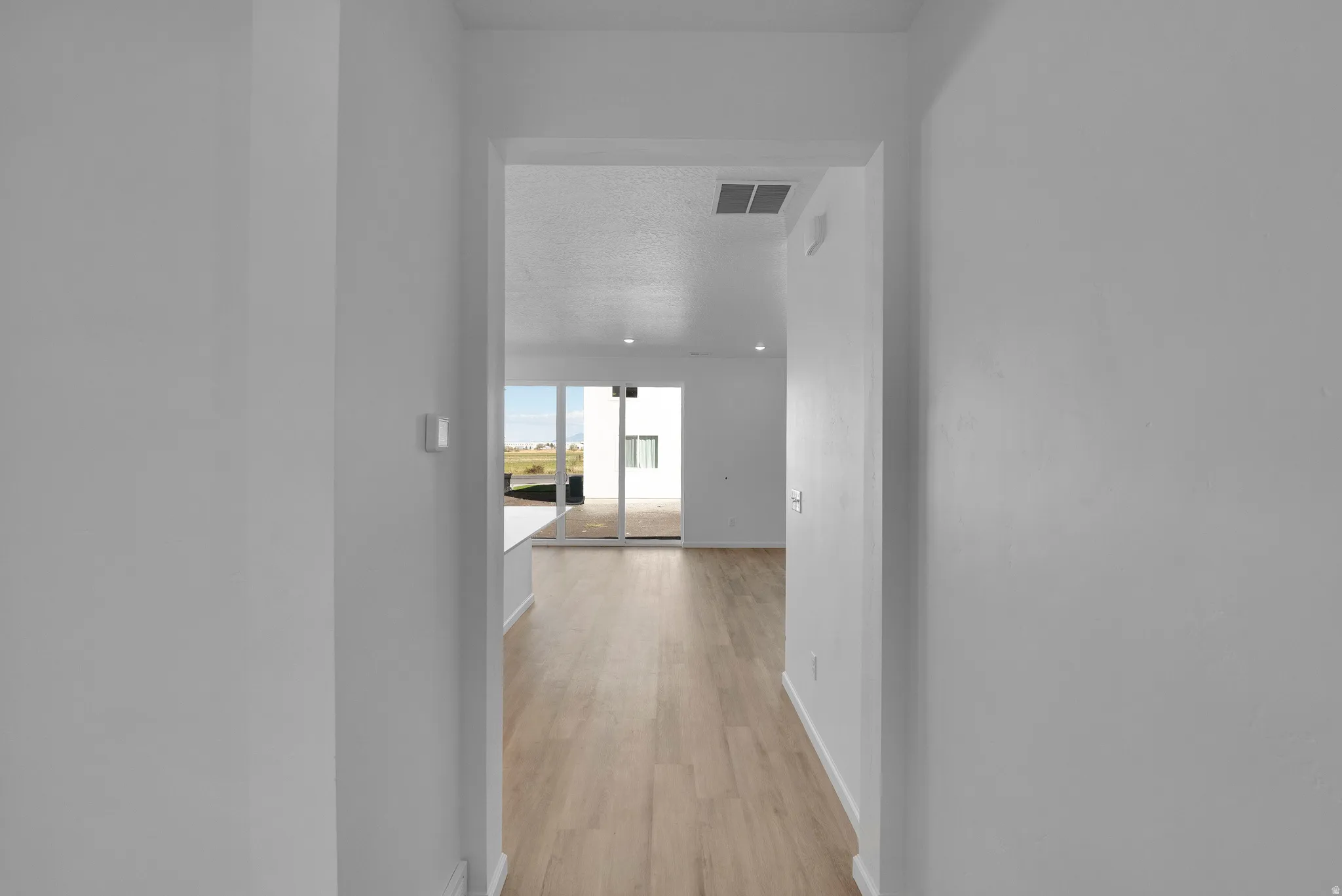 Corridor with light wood finished floors and a textured ceiling