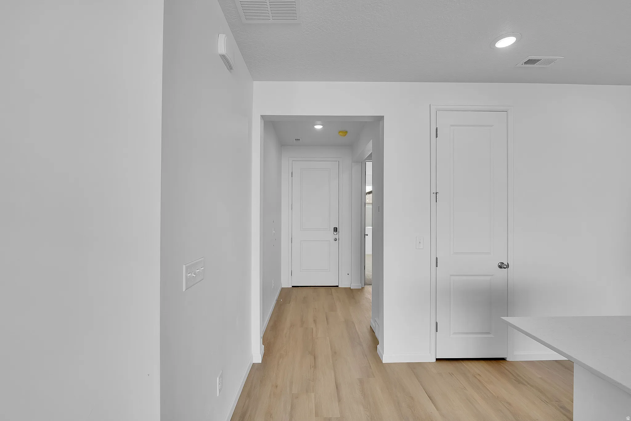 Hallway with light wood-style flooring and recessed lighting