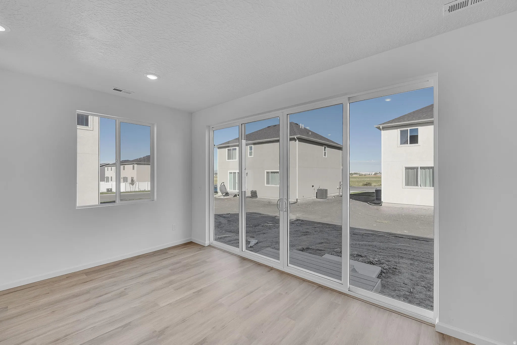 Unfurnished room with a textured ceiling and light wood-type flooring