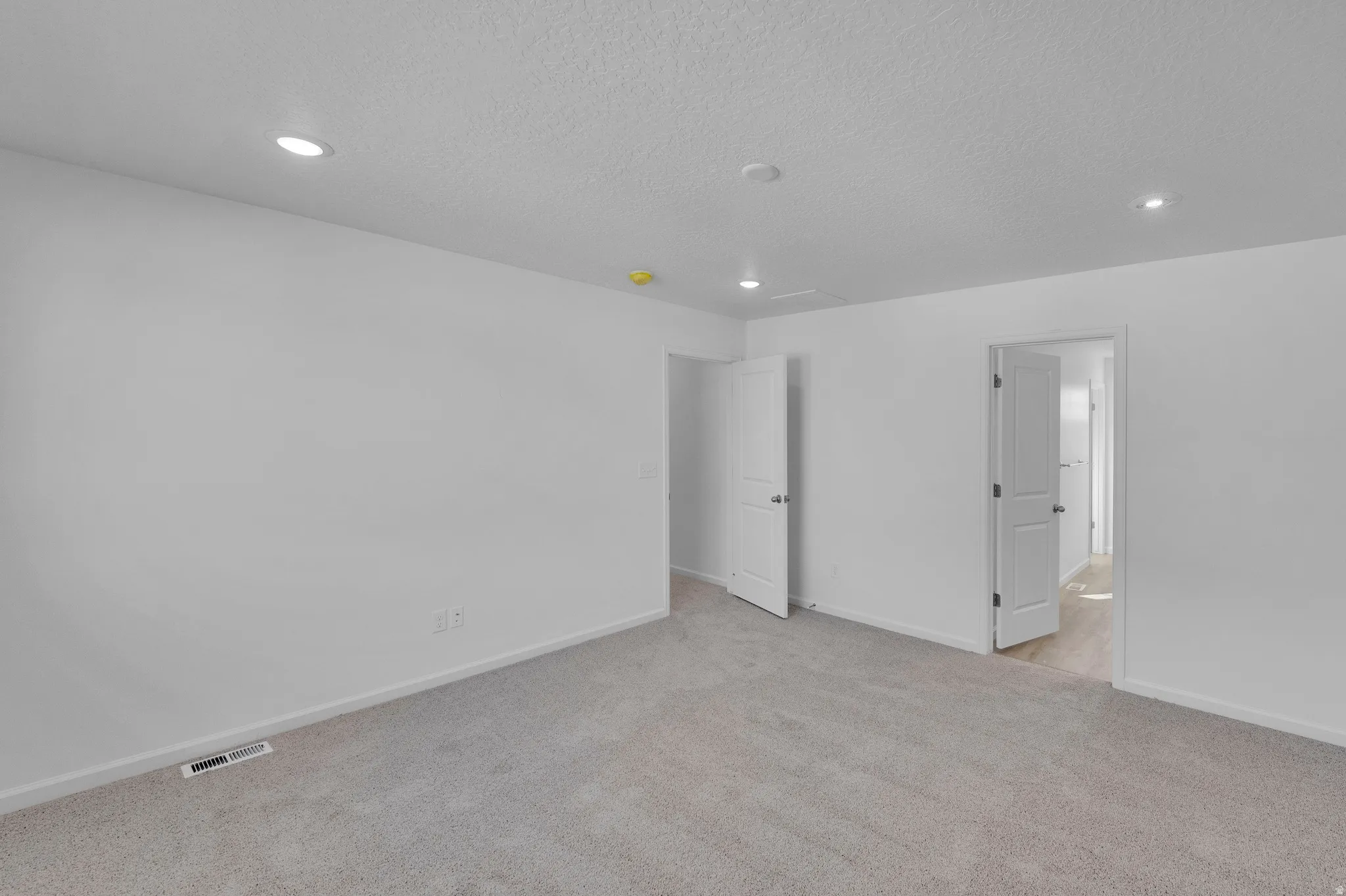 Unfurnished bedroom with light carpet, recessed lighting, and a textured ceiling