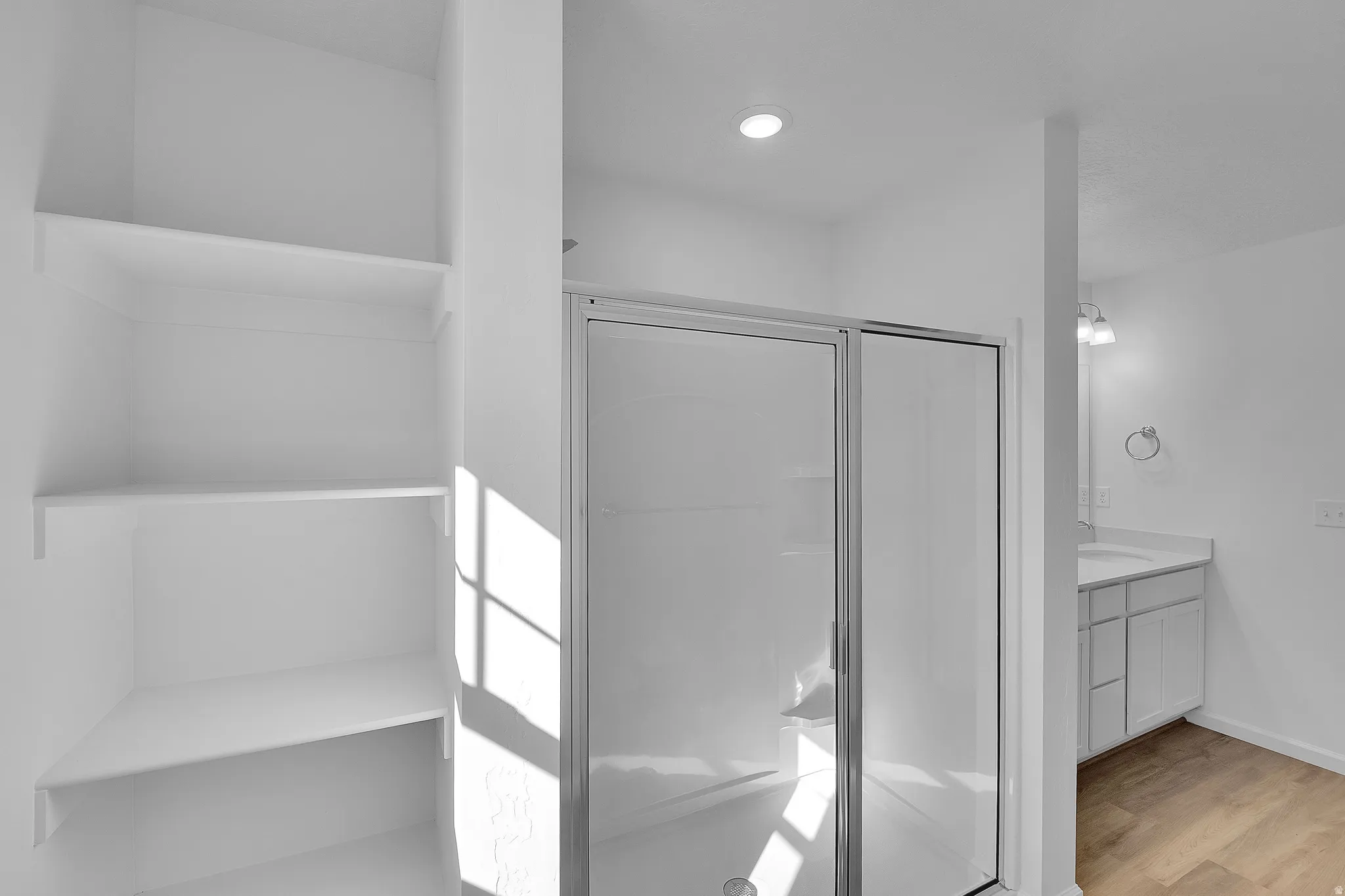 Bathroom featuring vanity, a stall shower, and light wood-type flooring