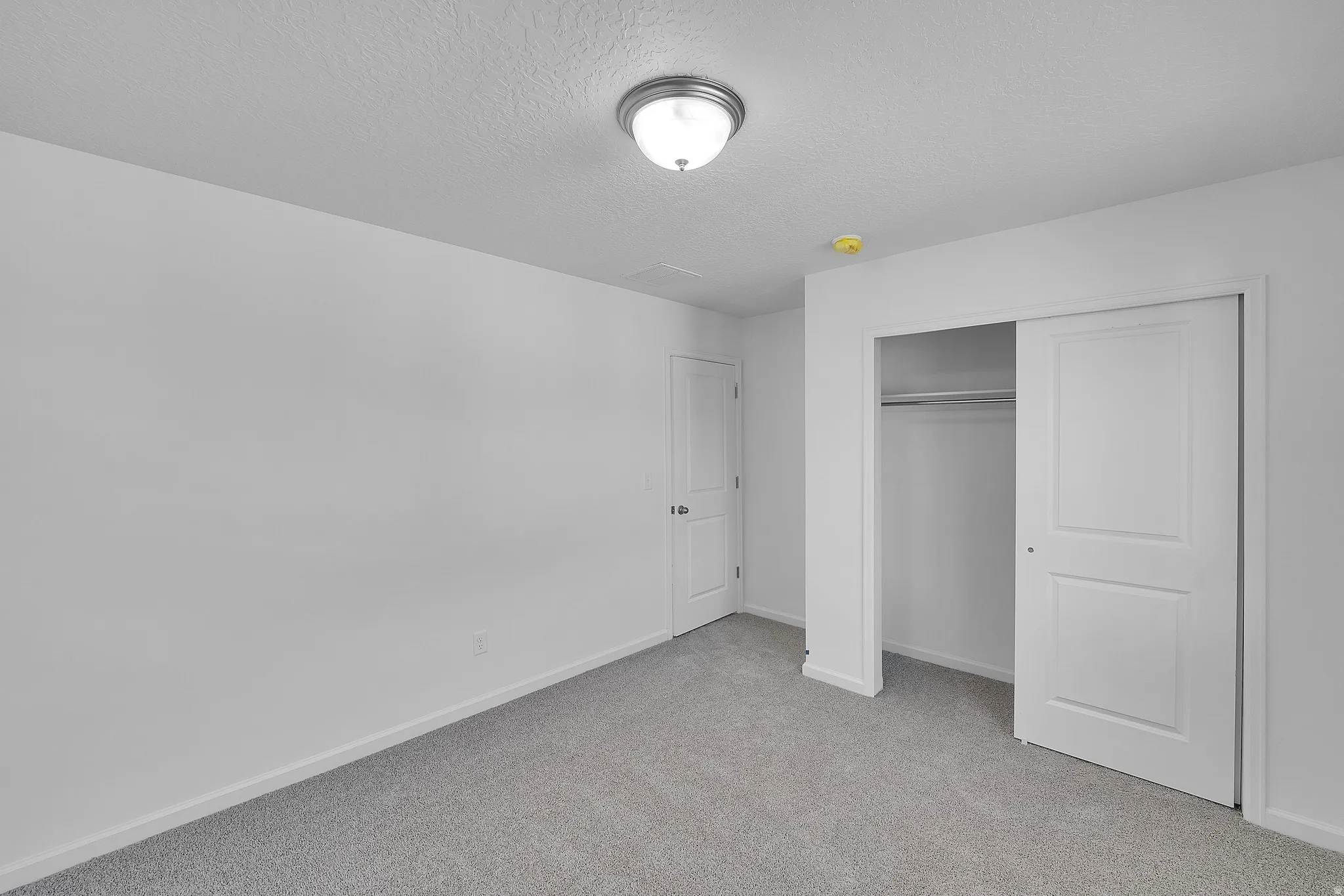 Unfurnished bedroom with light colored carpet, a textured ceiling, and a closet