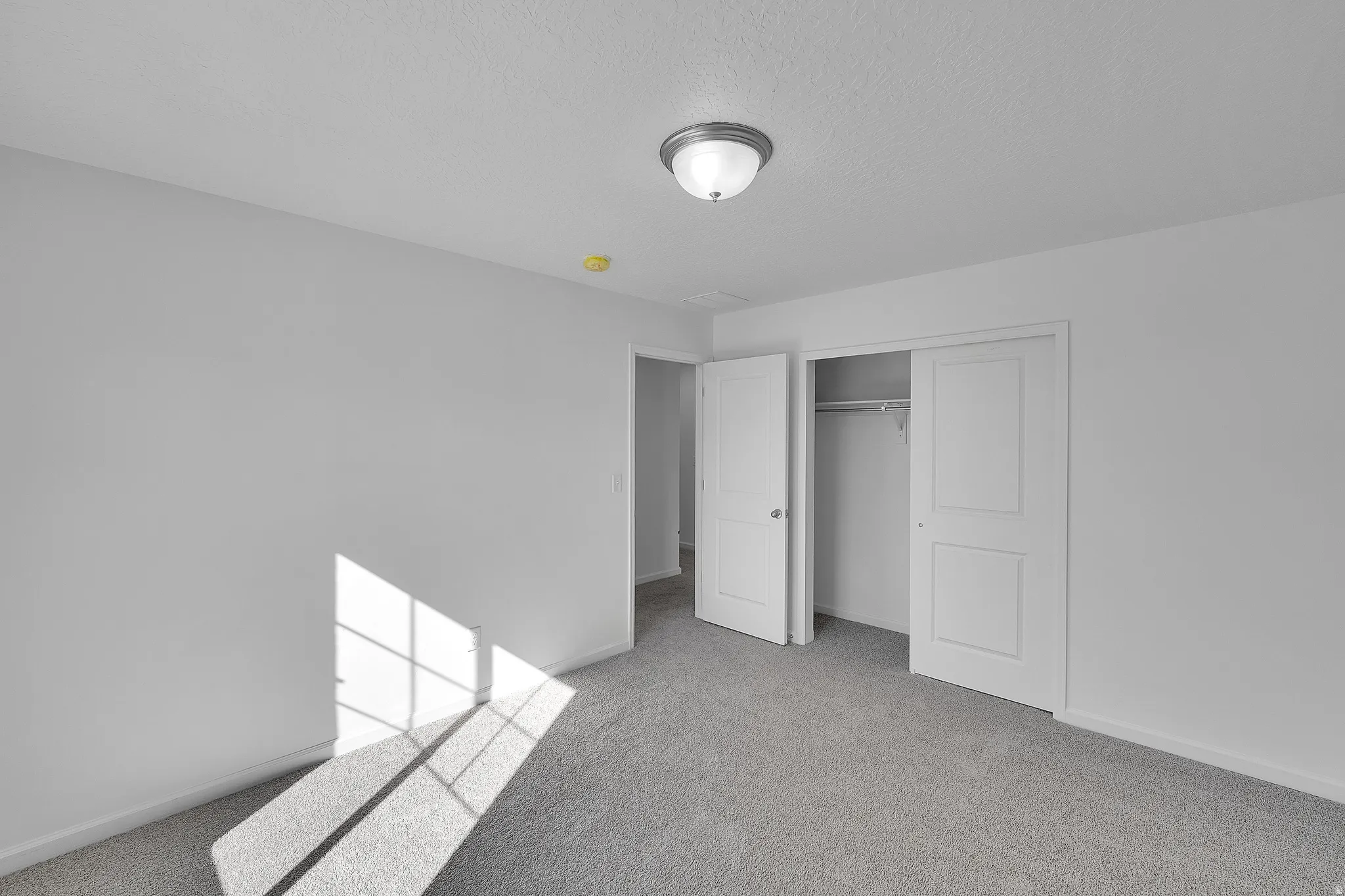 Unfurnished bedroom with a closet, light colored carpet, and a textured ceiling