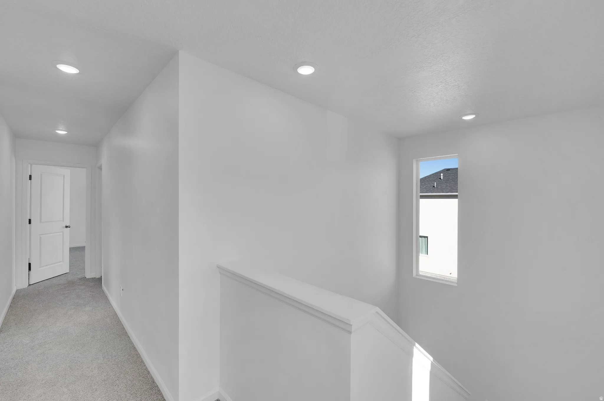 Hall with an upstairs landing, light carpet, and recessed lighting