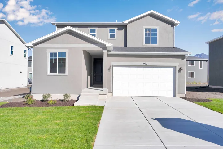 View of front of property with stucco siding, an attached garage, a front yard, and driveway