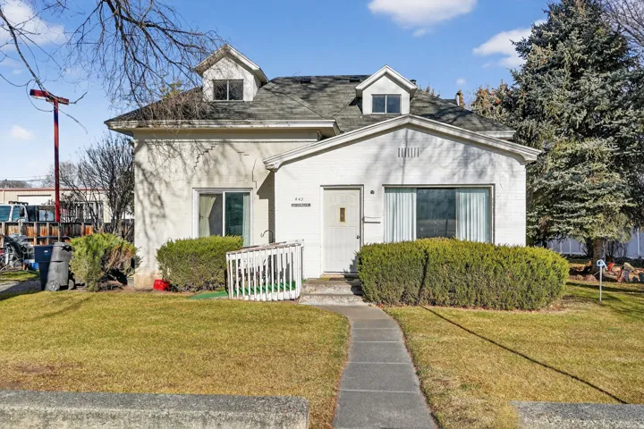View of front of home with a front yard, brick siding, and roof with shingles