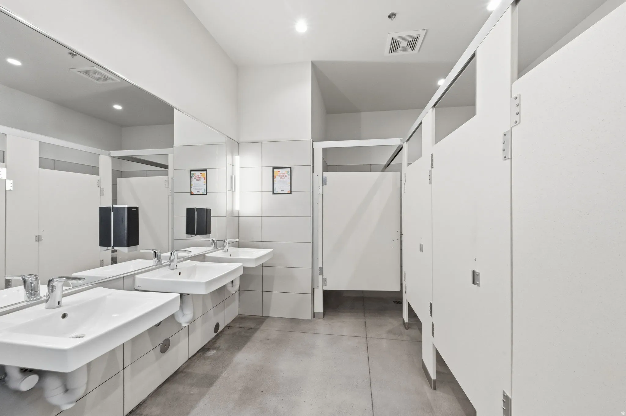 Bathroom featuring concrete floors, double vanity, and recessed lighting