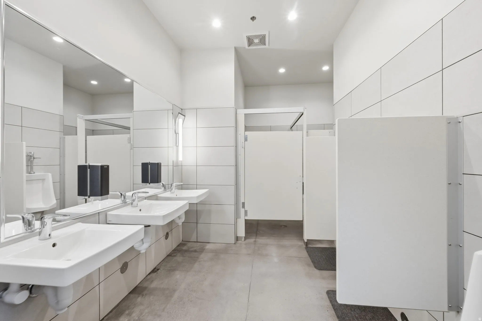 Full bath featuring concrete flooring, recessed lighting, and two vanities