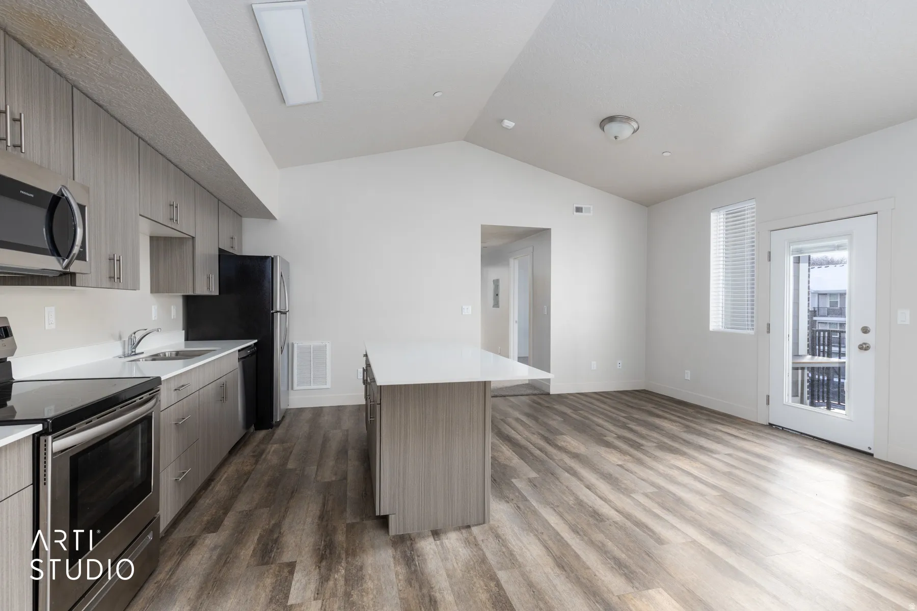 Kitchen featuring appliances with stainless steel finishes, lofted ceiling, modern cabinets, a center island, and dark wood-style flooring